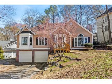 Charming split-level home with a two-car garage, brick accents, and well-maintained landscaping on a sunny day at 627 Radford Cir, Woodstock, GA 30188