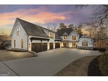 Stunning white farmhouse exterior with a spacious driveway and three-car garage at 4185 Etcetera Ln, Cumming, GA 30041