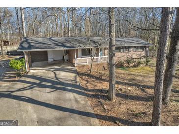 Brick home featuring attached carport, white railing, and a mature tree-lined lot at 6198 Rocky Creek Dr, Douglasville, GA 30135