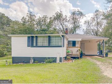 Charming single-story home with white siding, a covered carport, and a cozy front porch at 1202 Coan Dr, Locust Grove, GA 30248