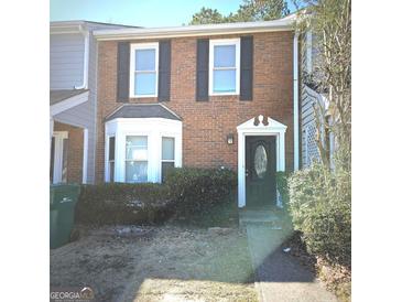 Charming brick townhome featuring a decorative front door and bay window at 8053 Woodlake Dr, Riverdale, GA 30274