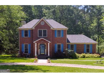 Charming two-story brick home with blue shutters, surrounded by lush greenery and mature trees, offers a welcoming ambiance at 230 Mapledale Trl, Sharpsburg, GA 30277