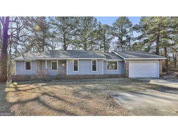 Charming single-story home with light blue siding, brick accents, and an attached garage at 6187 Radford Dr, Riverdale, GA 30296