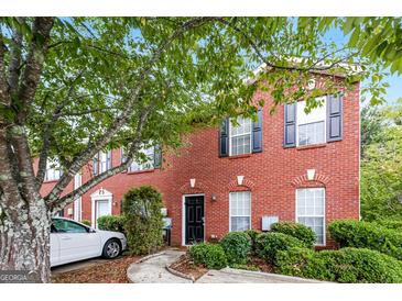 Charming brick townhome with manicured landscaping and a walkway leading to a black front door at 5797 Strathmoor Manor Cir, Lithonia, GA 30058
