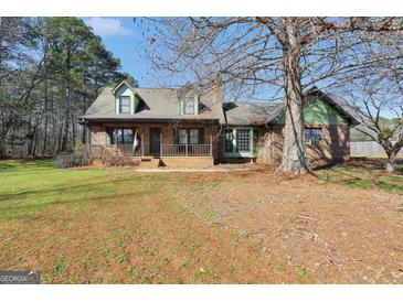 Charming brick home featuring dormer windows, a covered front porch, and mature trees in the front yard at 74 Price W Dr, Locust Grove, GA 30248