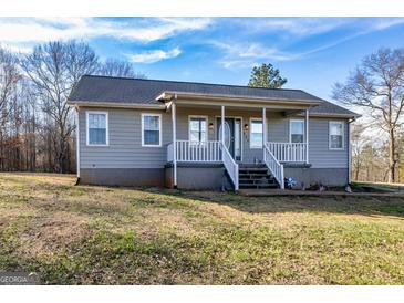 Inviting single-story home featuring a cozy front porch, well-maintained lawn and blue sky at 550 Stateline Rd, Bowdon, GA 30108