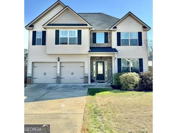 Two-story home with a three-car garage, black shutters, neutral siding, and brick entryway at 611 Winners Cir, Locust Grove, GA 30248