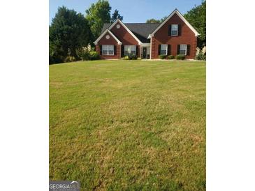 Charming two-story brick home with a well-manicured front lawn and mature trees at 65 Coldwater Way, Covington, GA 30016
