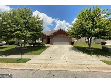 Charming one-story brick home with a two-car garage, lush lawn, and mature shade trees at 1687 Blue Heron Way, Hampton, GA 30228