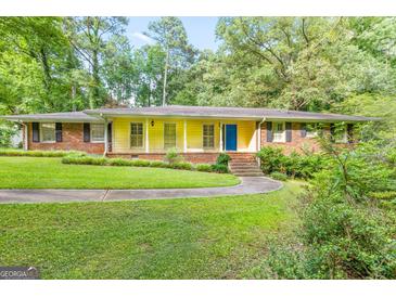 Charming ranch home with a bright yellow exterior, brick accents, blue door, and a well-manicured front lawn at 437 Forrest Ave, Fayetteville, GA 30214