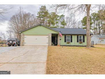 Charming green ranch home with a stone-accented garage, and an American flag at 11157 Ash Ct, Hampton, GA 30228