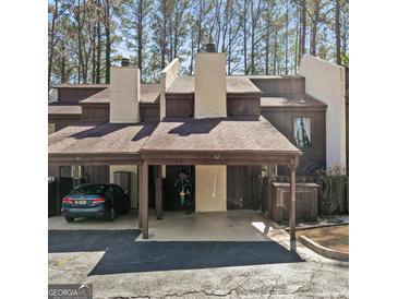 Charming townhome exterior with covered parking and wooded backdrop, offering a serene setting at 62 Cobblestone Crk, Peachtree City, GA 30269