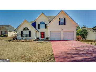 Two-story home with a red driveway, a two-car garage, and a manicured front lawn at 477 Harvick Cir, Stockbridge, GA 30281