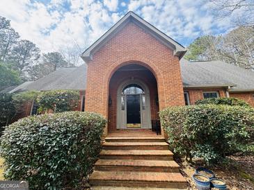 Charming brick home featuring a beautiful arched entrance, manicured bushes, and a welcoming front entrance at 9255 Betony Wood Trl, Jonesboro, GA 30236