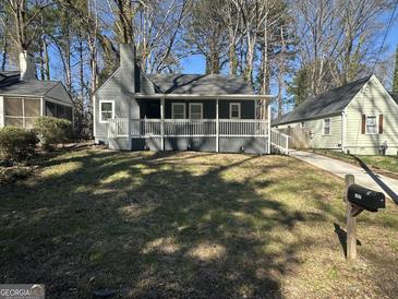 Charming gray home featuring a covered front porch, a well-maintained lawn, and mature trees at 1457 Richland Sw Rd, Atlanta, GA 30310