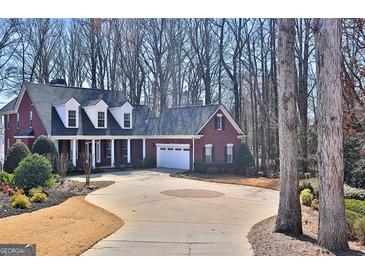 Charming red brick home featuring a circular driveway and attached garage, nestled amongst mature trees at 127 Eagles Club Dr, Stockbridge, GA 30281