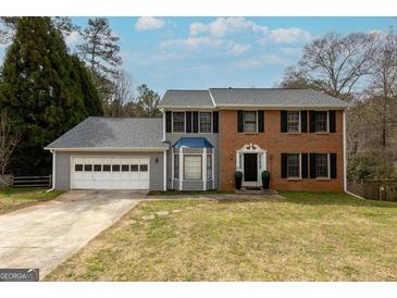 Charming two-story home featuring a brick facade, gray siding, bay window, and a two-car garage at 1399 Fawnbrook Ct, Lilburn, GA 30047