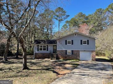 Charming split-level home features a brick facade, attached garage, and mature trees in the front yard at 4935 Liberty Sw Ct, Stone Mountain, GA 30087