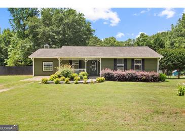Charming single-story home with a well-manicured lawn, flowerbeds, and a cozy front porch at 888 Laney Rd, Locust Grove, GA 30248