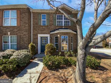 Charming brick townhome featuring a quaint front door and beautifully landscaped walkway at 11403 South Grove Dr, Hampton, GA 30228