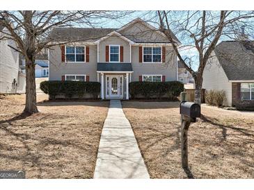 Charming two-story home featuring neutral siding, red shutters, and mature trees at 6746 Lake Erie Ln, Fairburn, GA 30213