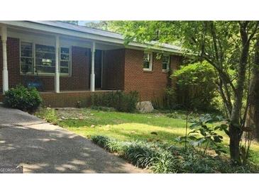 Brick home with covered porch, lawn, and mature trees creating a welcoming facade at 2317 Hillside Rd, Riverdale, GA 30296