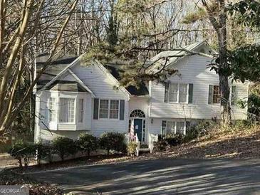 Charming two-story home with light siding, dark shutters, and a welcoming front porch surrounded by lush greenery at 132 Springwater Trce, Woodstock, GA 30188