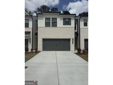 New townhome featuring a gray two-car garage, painted brick, modern black trim and shutters, and concrete driveway at 984 Sutherland Ln # 31, Lawrenceville, GA 30043