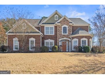 Charming two-story brick home featuring manicured lawn, multi-pane windows, and arched entry at 6142 Golf View Xing, Locust Grove, GA 30248