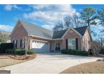 Charming one-story brick home featuring an attached two-car garage and manicured front yard at 265 Fenwyck Commons, Fayetteville, GA 30214