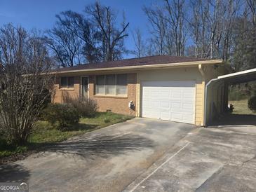 Charming brick home featuring a one car garage and covered parking at 67 Rosser Ln, Locust Grove, GA 30248