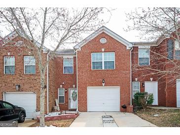 Charming brick townhome with a one car garage and a well maintained front yard and inviting front door at 6517 Snowbird Ln, Douglasville, GA 30134