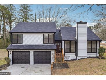 Two-story home featuring a gray roof, two car garage and a well manicured lawn at 1015 Chapman Ln, Stone Mountain, GA 30088