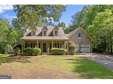 Charming home with a welcoming front porch, well-manicured landscaping, and a two-car garage with basketball hoop at 9209 W Banks Mill Rd, Winston, GA 30187