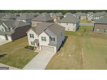 An aerial view of a two-story home with a spacious front yard and a long concrete driveway at 316 Denton Way, Hampton, GA 30228