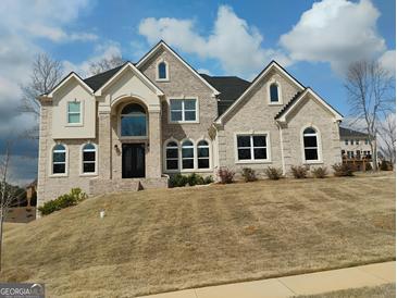 Beautiful two-story home with light brick and elegant architectural design, set against a clear blue sky at 4604 Mossey Dr, Stonecrest, GA 30038