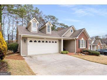 Charming home featuring a two-car garage, a mix of stucco and brick, and dormer windows on a neatly manicured lawn at 103 Augusta Dr, Peachtree City, GA 30269