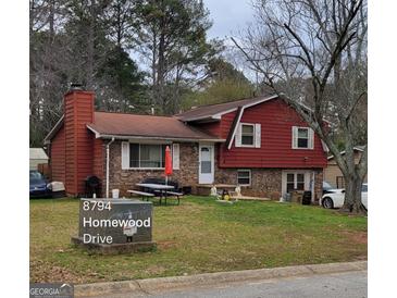 Charming home featuring a brick and wood facade, complemented by a cozy front yard and an outdoor picnic area at 8794 Homewood Dr, Riverdale, GA 30274