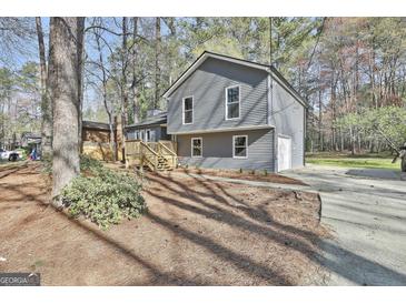 Attractive two-story home with gray siding, wooden deck, and lush landscaping at 1967 Levgard Ln, Riverdale, GA 30296