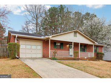 Charming single-story brick home featuring an attached garage, a welcoming front porch, and a well-maintained lawn at 979 Walnut Creek Ln, Jonesboro, GA 30238