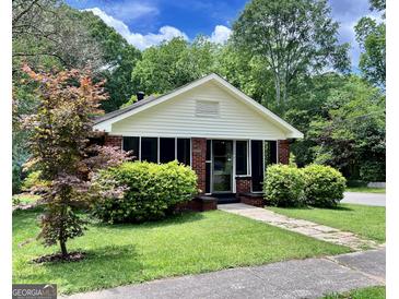 Charming brick home featuring a cozy front porch and lush landscaping at 2791 Pearl St, East Point, GA 30344
