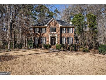 Charming two-story brick home featuring a classic design with well-maintained landscaping and mature trees surrounding the property at 302 Cumberland Ct, Peachtree City, GA 30269