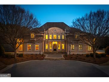Elegant two-story home featuring a grand entrance, manicured landscaping, and a circular driveway at twilight at 300 Annelise Park Dr, Fayetteville, GA 30214