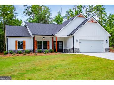 Charming home featuring white siding, a black roof, wood accents, a well-manicured lawn, and an attached two-car garage at 3264 Greenhill Ct, Villa Rica, GA 30180