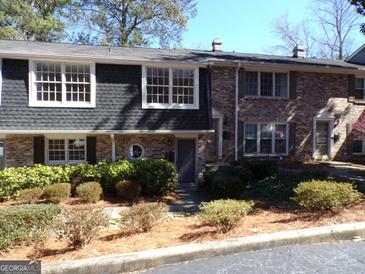 Brick townhome featuring well-maintained landscaping, a grey shingled section, and multiple windows for ample natural light at 2401 Northlake Ct, Atlanta, GA 30345