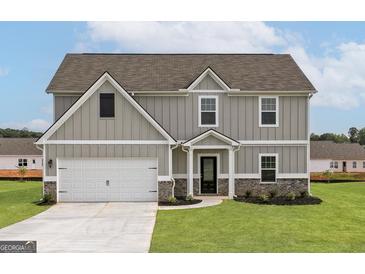 Charming two-story home featuring gray siding, brick accents, attached garage, and a well-manicured lawn at 275 Oliver Dr, Locust Grove, GA 30248