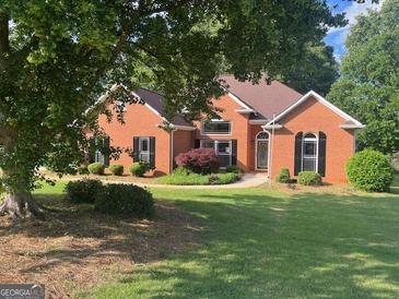 Charming brick home featuring a manicured lawn and mature trees, perfect for outdoor enjoyment at 704 Euel Dr, Mcdonough, GA 30252