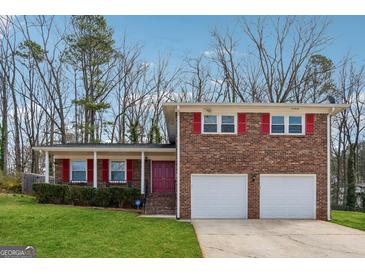 Charming brick home with a two car garage, red shutters, green lawn and mature trees at 3216 Pheasant Dr, Decatur, GA 30034