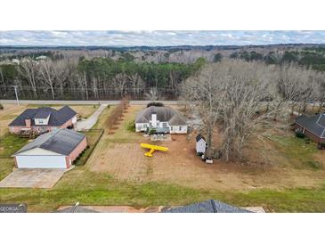 Expansive aerial view of the charming home featuring a large lot, outbuildings, and a patio seating area at 3403 Bill Gardner Pkwy, Locust Grove, GA 30248