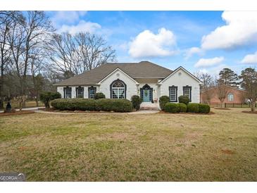 Charming white brick home with a well-manicured lawn and a bright blue front door at 3403 Bill Gardner Pkwy, Locust Grove, GA 30248
